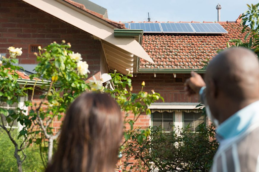 A sustainability consultant speaking with a homeowner outside their home, about solar panels