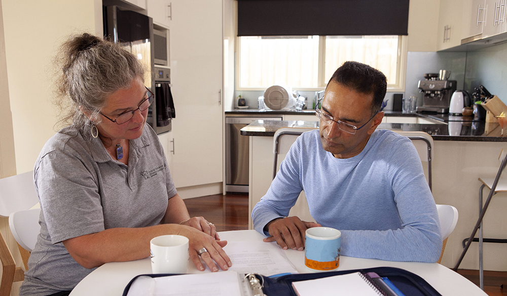 A sustainability assessor seated at the table with a householder, discussing how to reduce their energy bills.