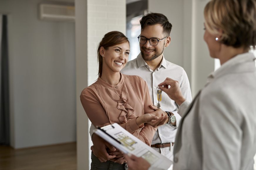 Real estate agent handing over the keys to a young couple