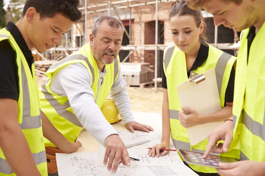 Builder with tradies looking over building plans onsite