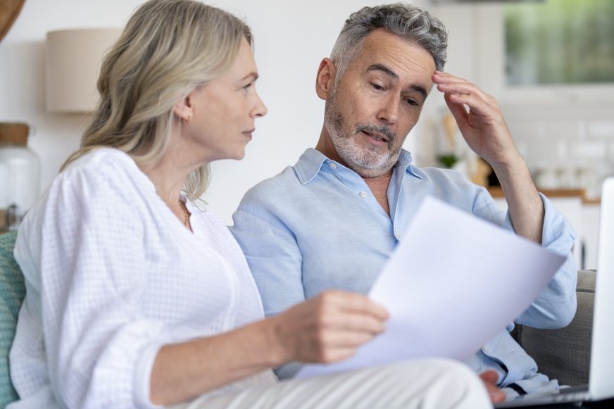 A couple looking worried, while inspecting their home energy bill.