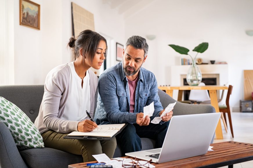 Couple researching on laptop and taking notes