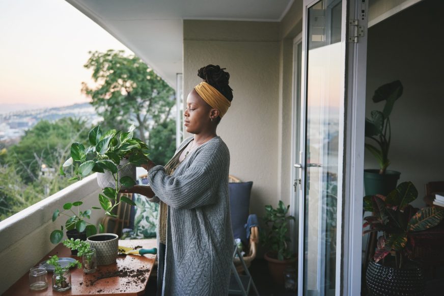 Woman tending to plants on apartment balcony