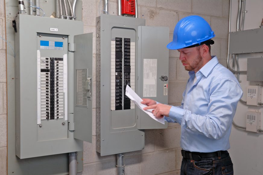 Engineer looking at file in front of control panel in utility room