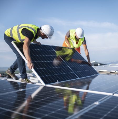 Team of two engineers installing solar panels on roof.
